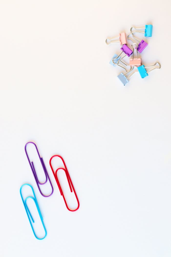 Top view of stationery supply of various bright metallic clips with rounded edges on smooth surface